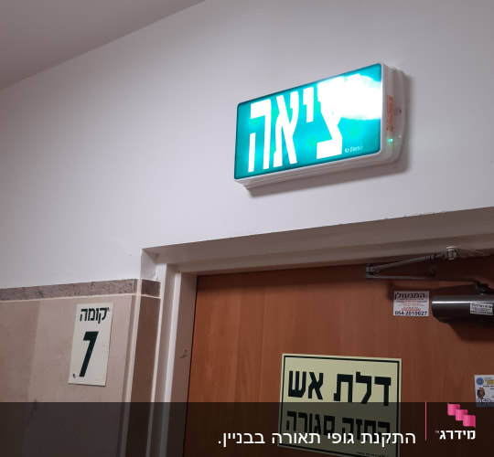 שלט יציאה מואר מעל דלת עץ